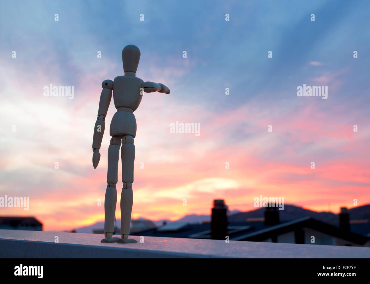 Wooden dummy pointing with his finger towards the horizon at sunset Stock Photo