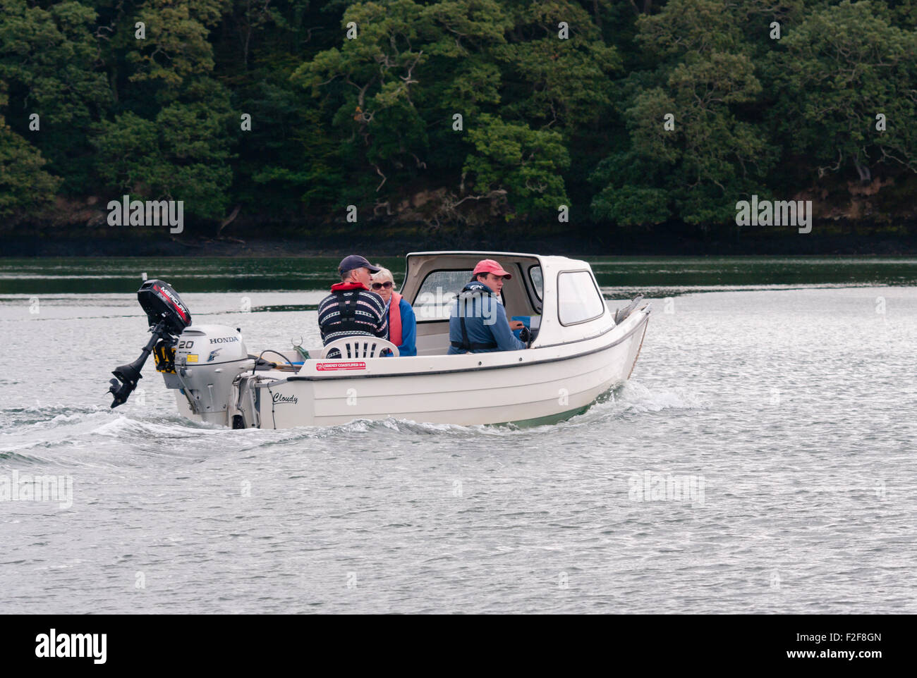 3 People In A Small Boat With an Outboard Motor On The River Truro