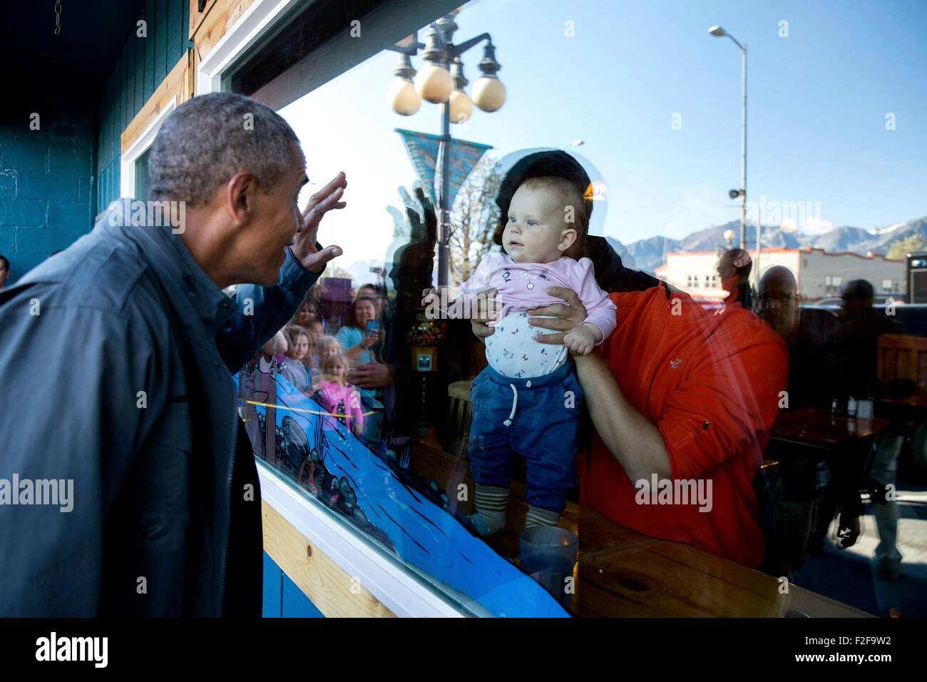 U.S. President Barack Obama waves to a baby as he walks to get an ice cream during a visit to the Kenai Fjords National Park September 1, 2015 in Seward, Alaska. Stock Photo