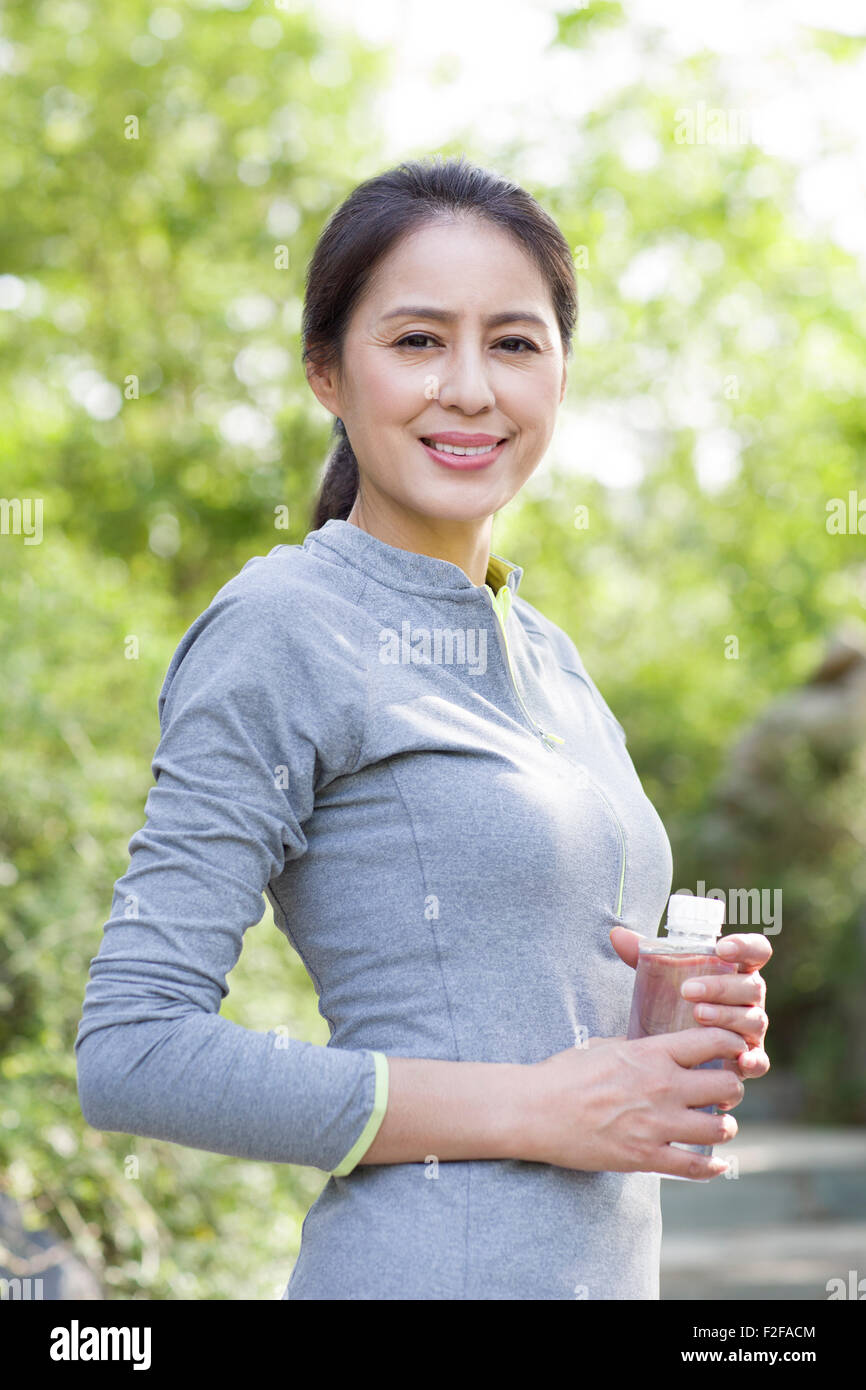 Happy mature woman holding bottled water after exercising Stock Photo