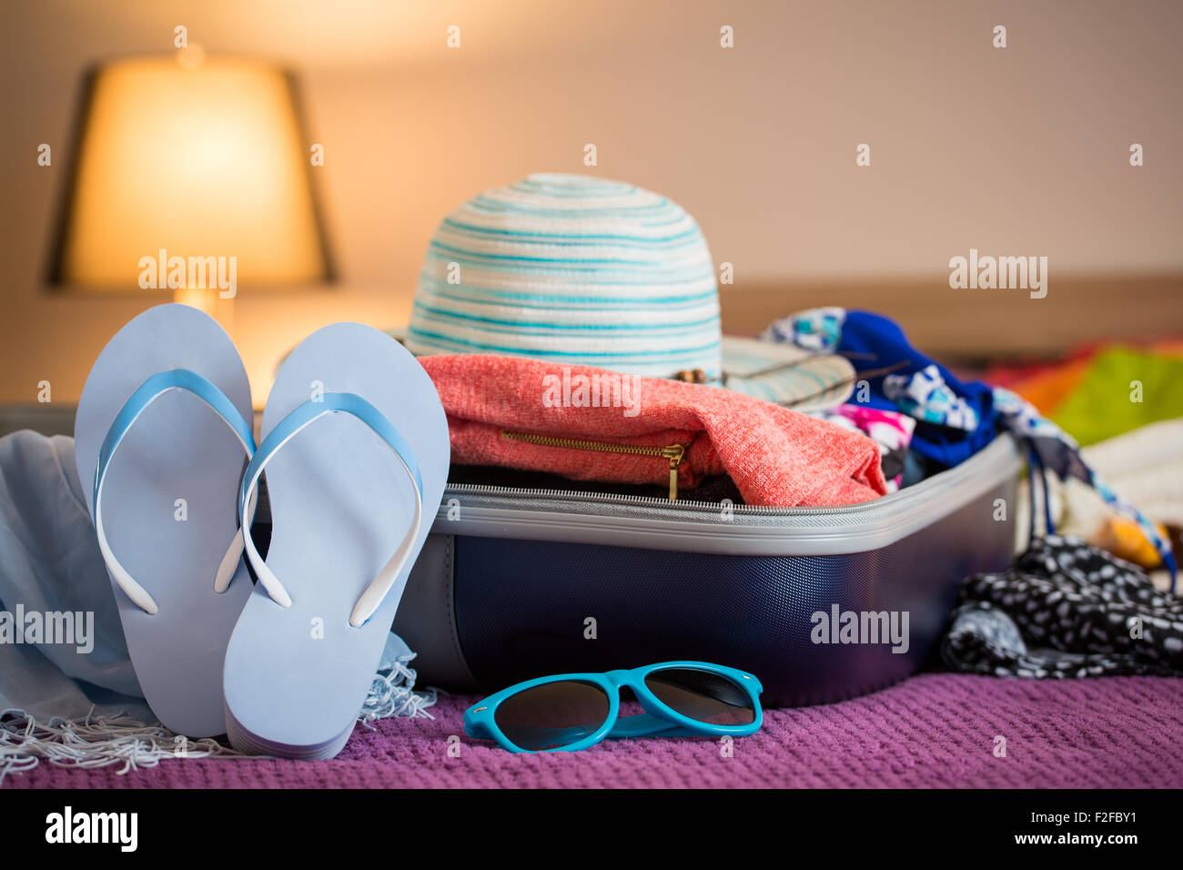 Open suitcase with clothing in the bedroom. Summer holiday concept. Stock Photo