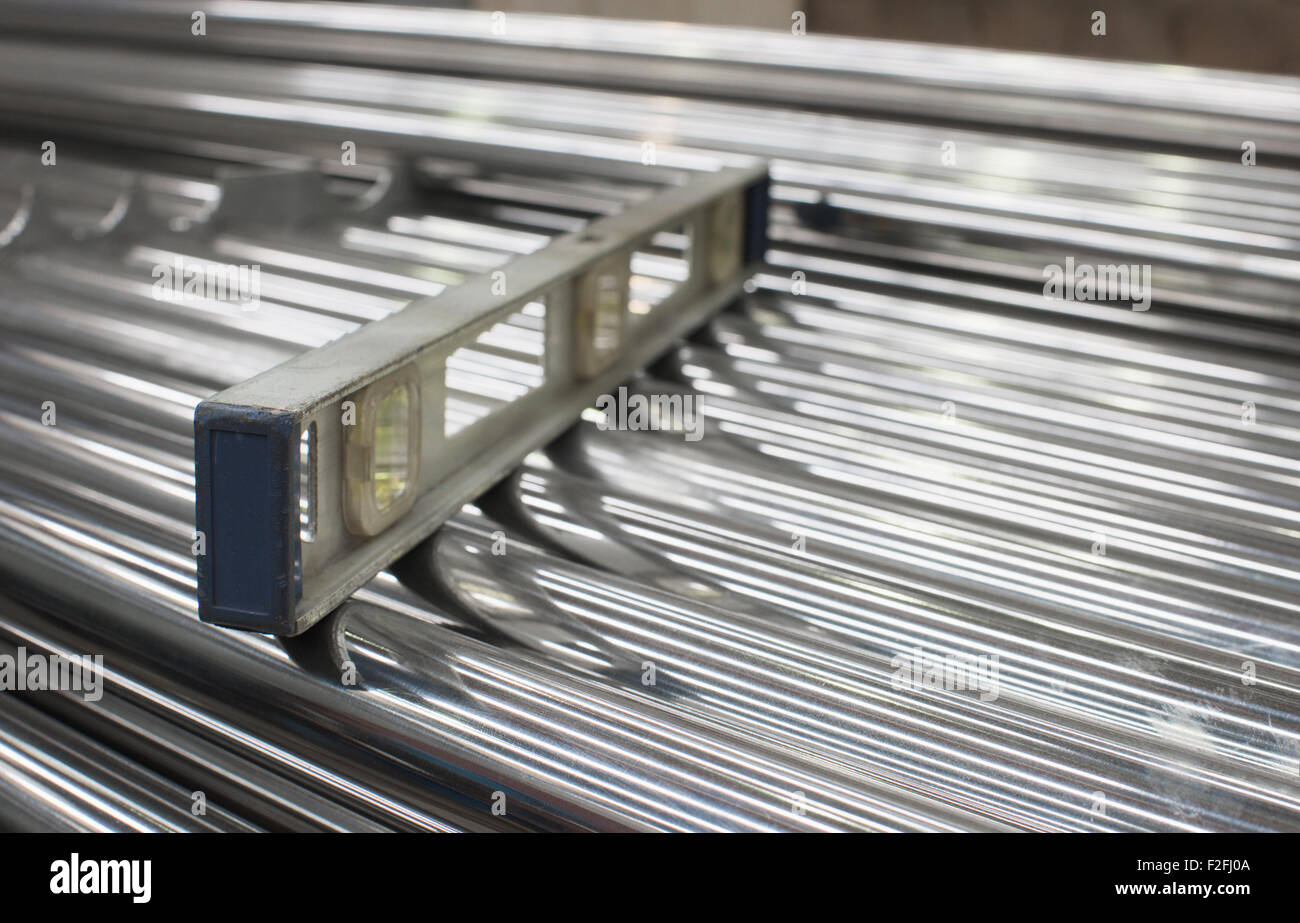 Level on a stack of steel tubes. Very shallow depth of field with only the nearest tubes and end of the level in focus. Stock Photo
