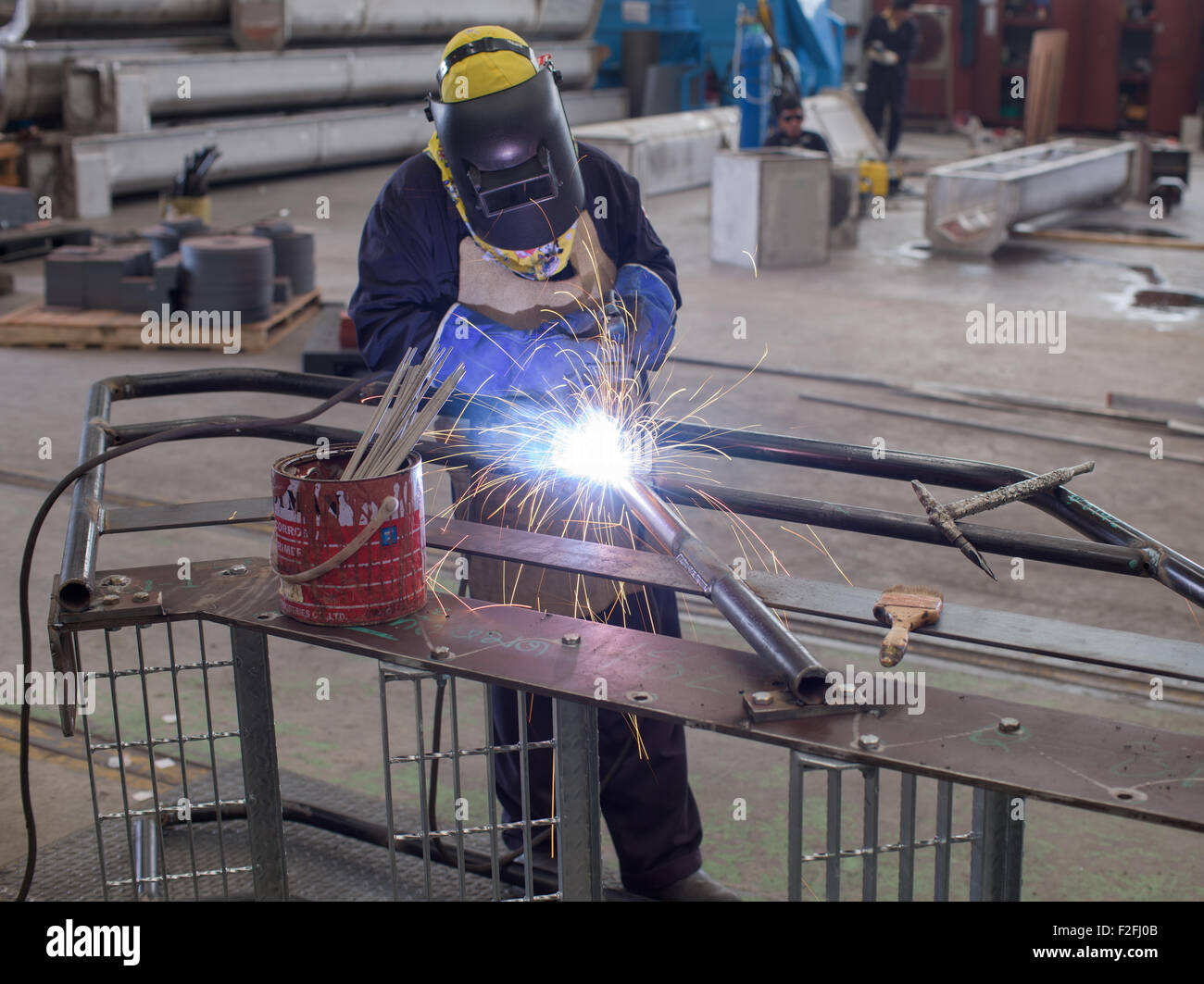 Welder with protective gear welding a metal, industrial staircase at a