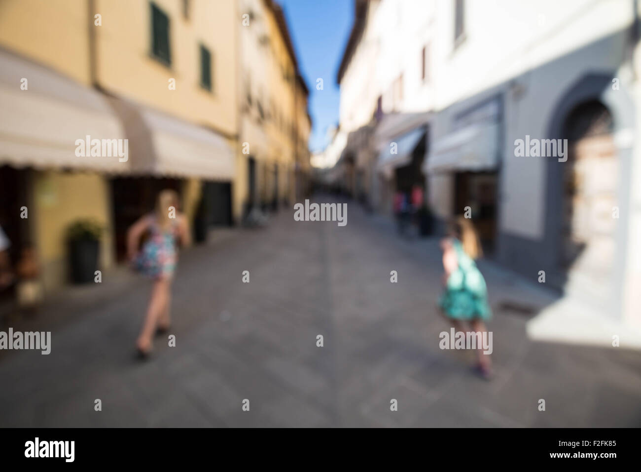 Two girls running away from camera, outside in a European town. Out of focus shot for use as a background Stock Photo
