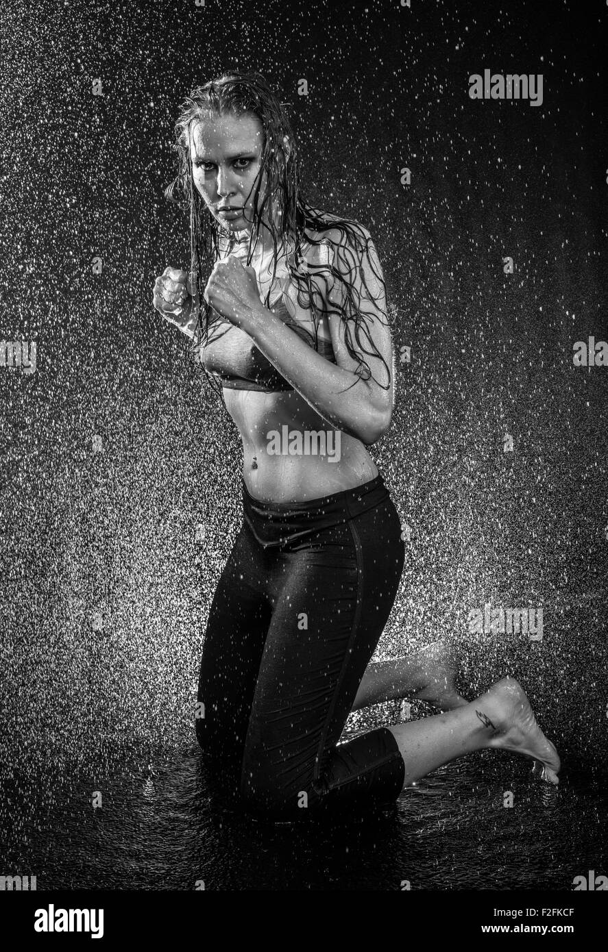 Athletic Woman Kneeling in Boxing Stance in Studio Stock Photo