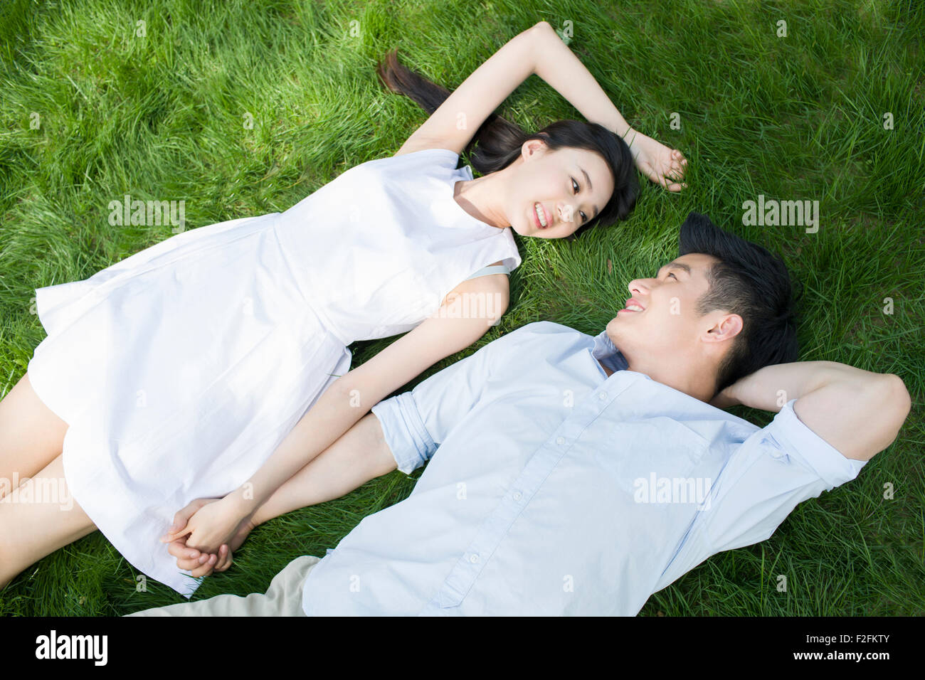Happy young couple lying on grass Stock Photo - Alamy