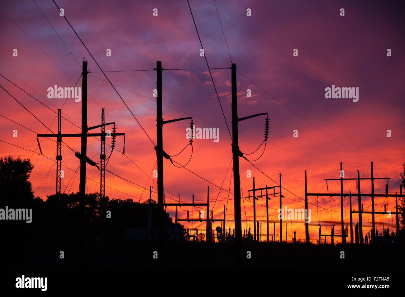 An electrical substation silhouetted against a vivid sunset sky. Stock Photo
