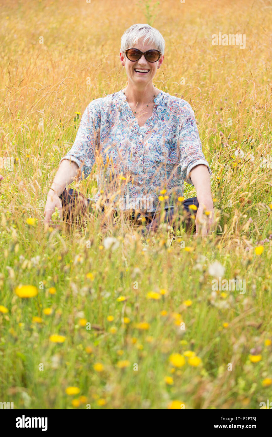 Portrait senior woman sitting cross-legged in rural field Stock Photo