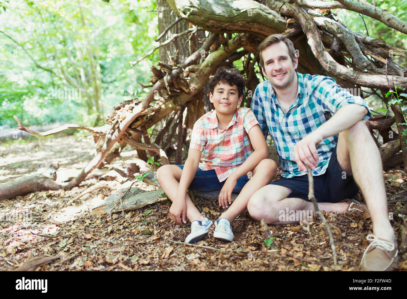 Portrait smiling father and son in woods Stock Photo