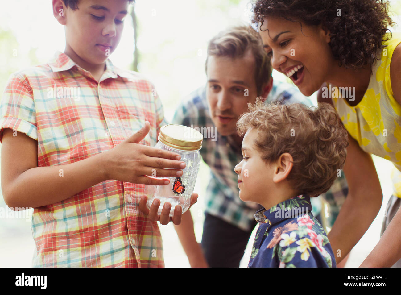 Family watching butterfly in jar Stock Photo