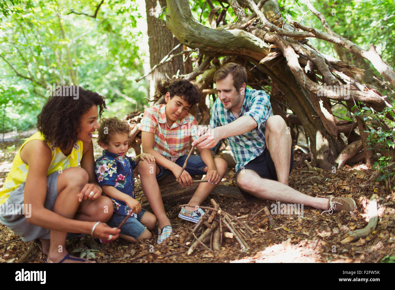 Family making small campfire in woods with sticks Stock Photo