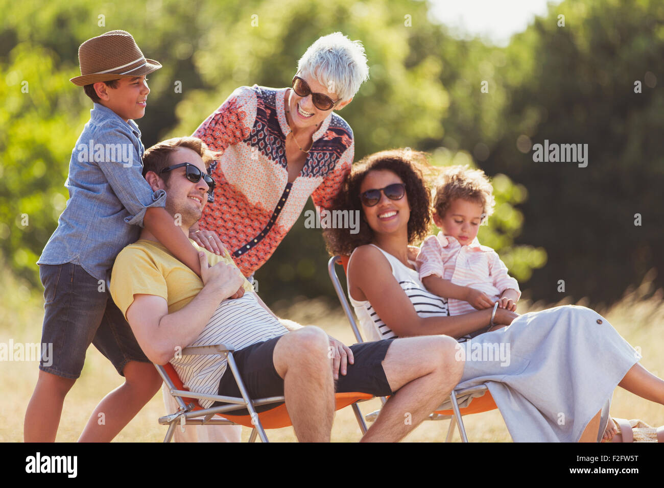 Multi-generation family relaxing in sunny field Stock Photo