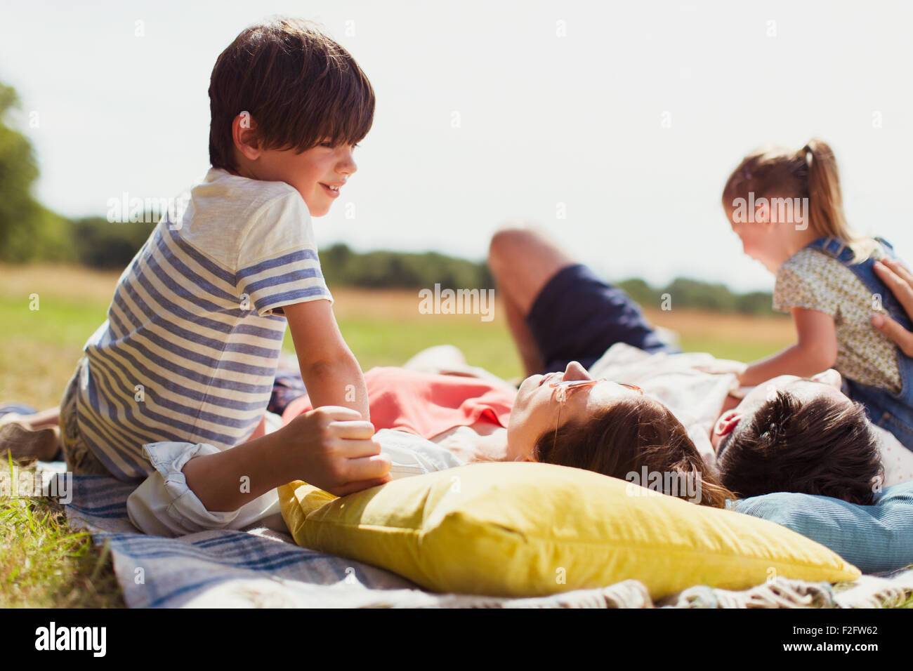 Family relaxing on blanket in sunny field Stock Photo