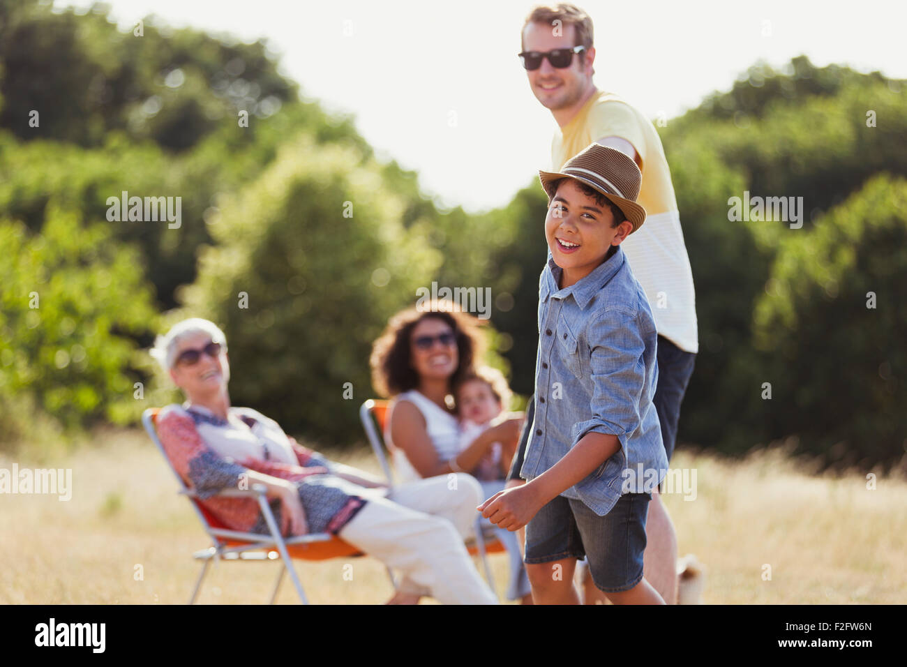 Portrait playful son pulling father in sunny field Stock Photo