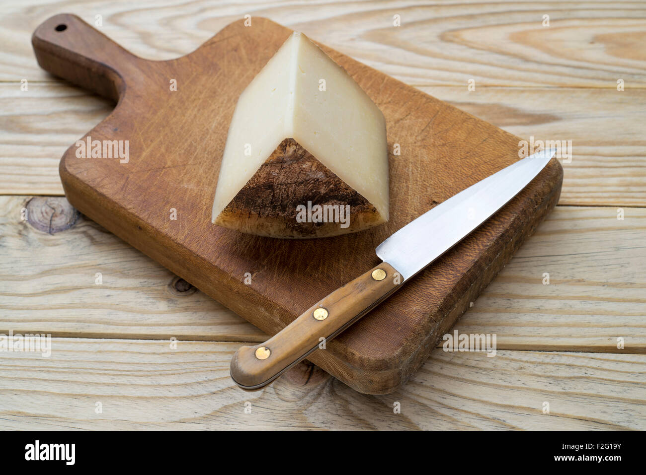 Cheese and knife on cutting board Stock Photo