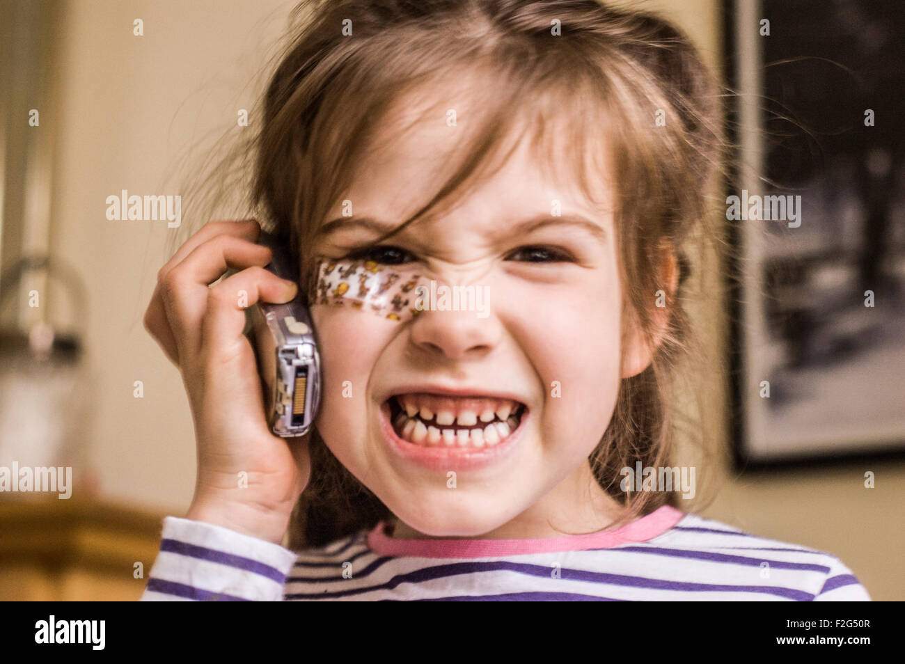 An aggressive growl by a beautiful young girl on the phone with a plaster on her face Stock Photo