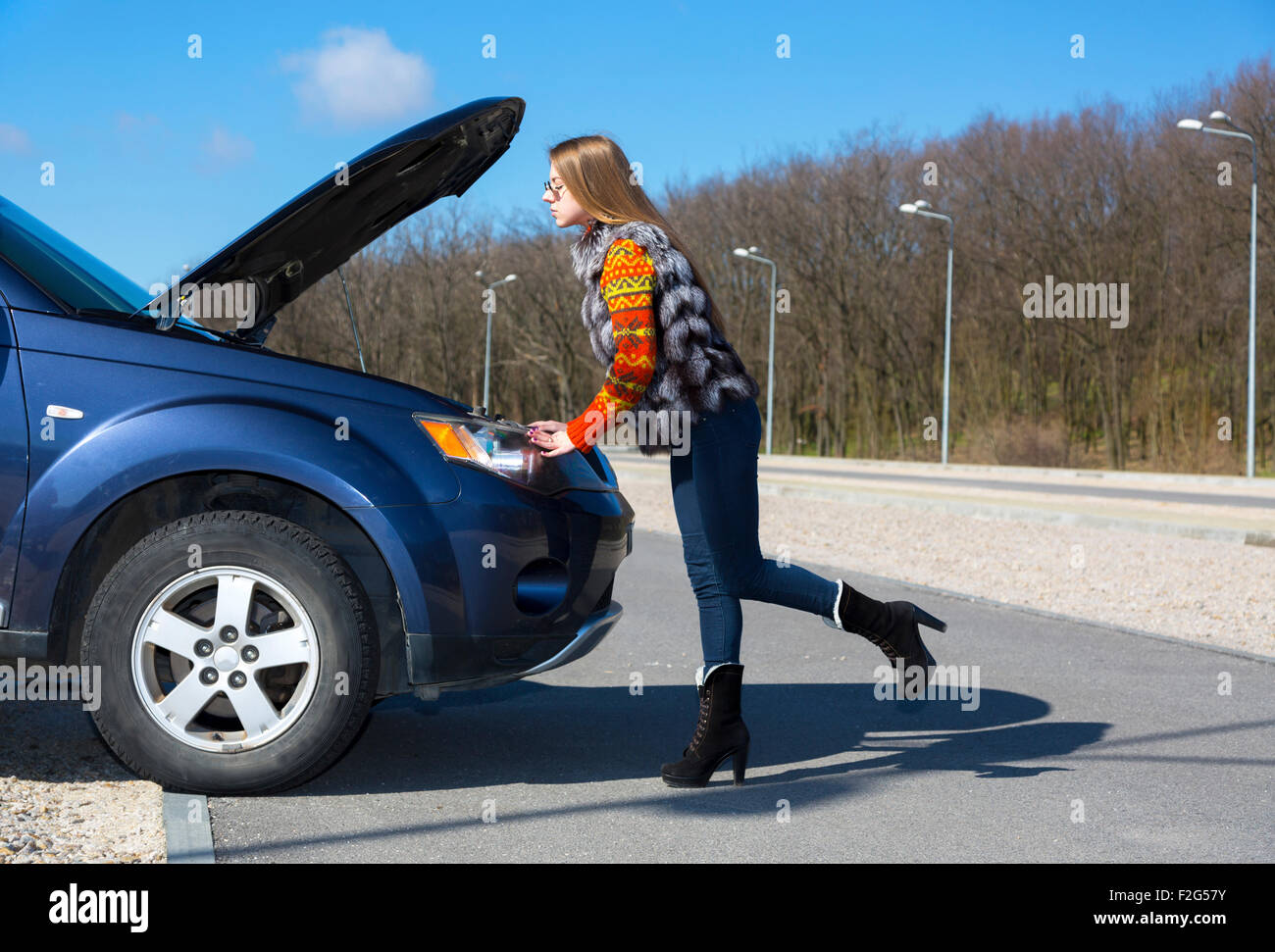 Female driver inspects her car engine Stock Photo