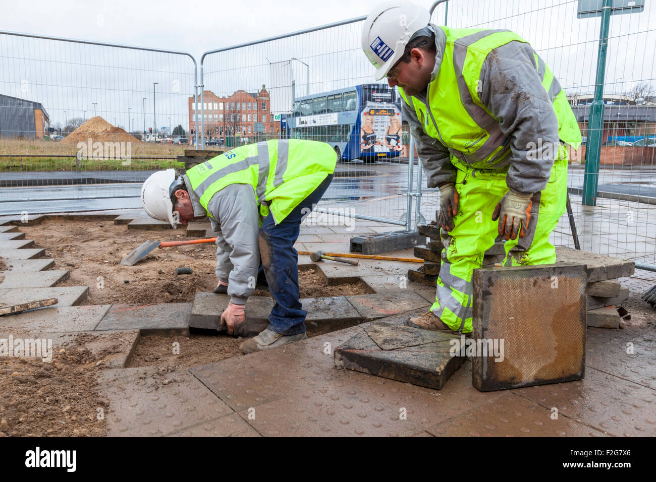 Workers laying tactile paving tiles and standard paving slabs. Nottingham, England, UK Stock Photo