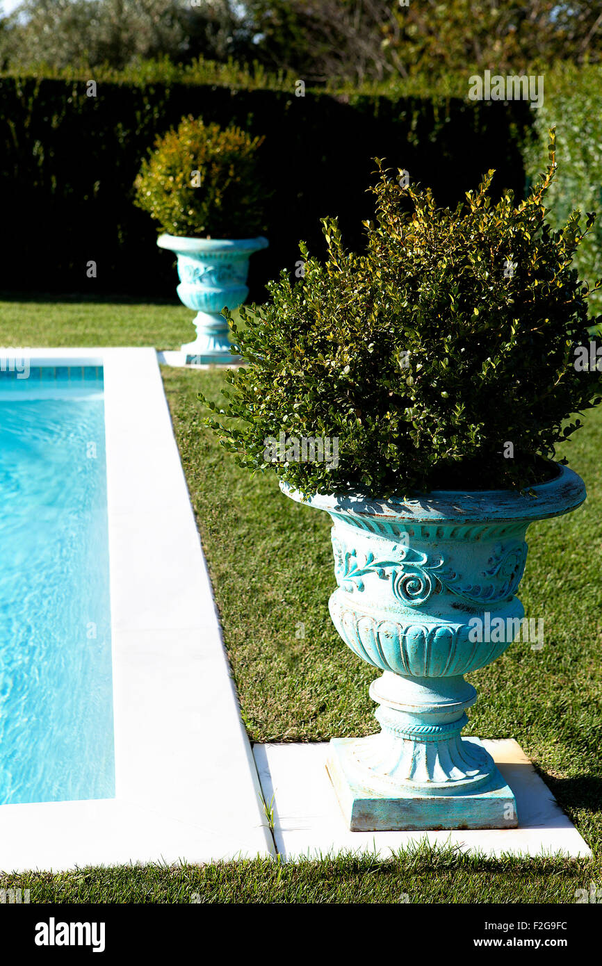 Swimming pool in garden decorated with urn flower pots Stock Photo