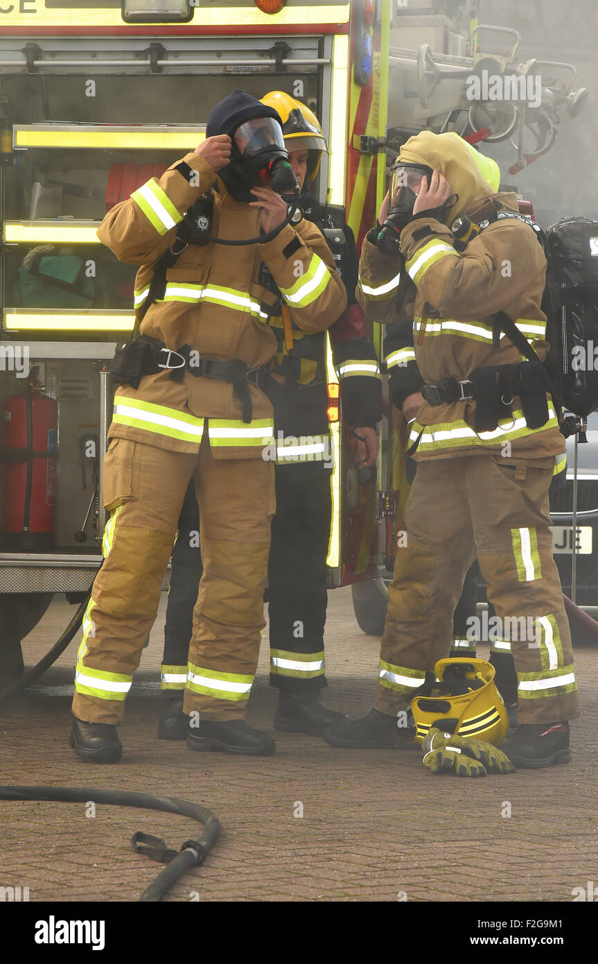 Firefighters in breathing apparatus check their kit amid smoke from a fire Stock Photo