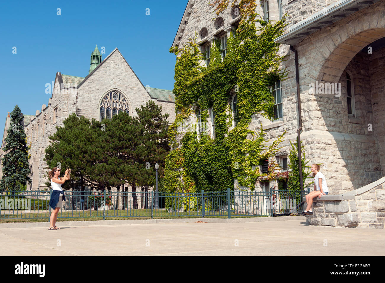 Woman taking a picture of her daughter in front of the Ontario Hall building,  Queen's University, Ontario, Canada. Stock Photo