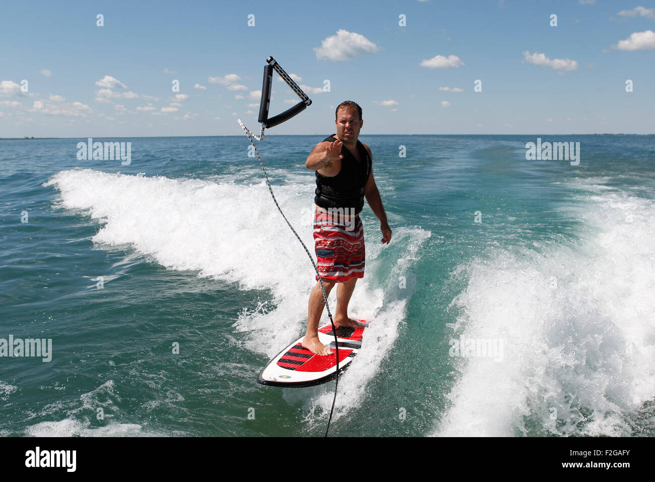 A man throwing the tow rope back to the boat while wakesurfing Stock