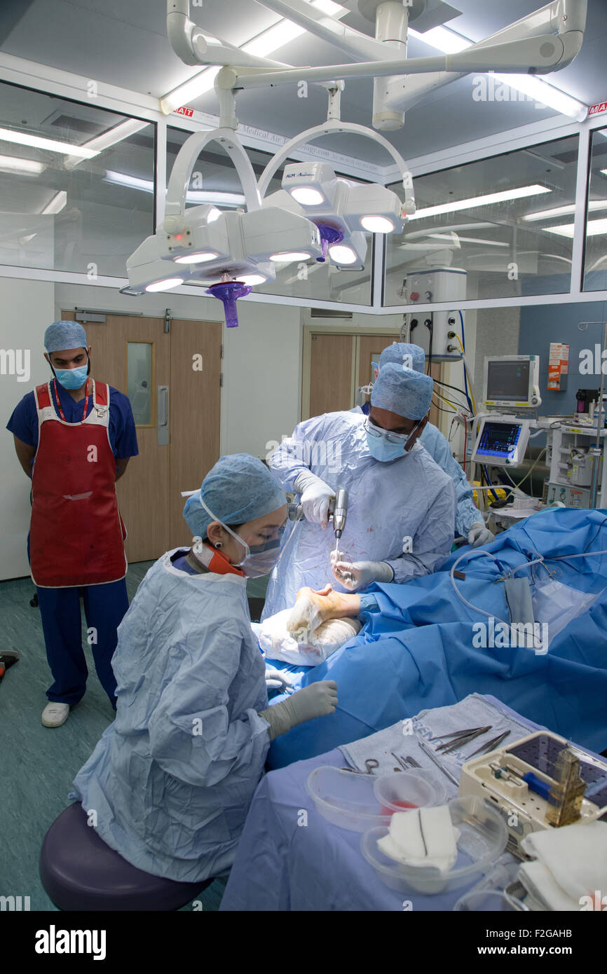 Surgeon and medical staff working in an operating theatre in an NHS hospital Stock Photo