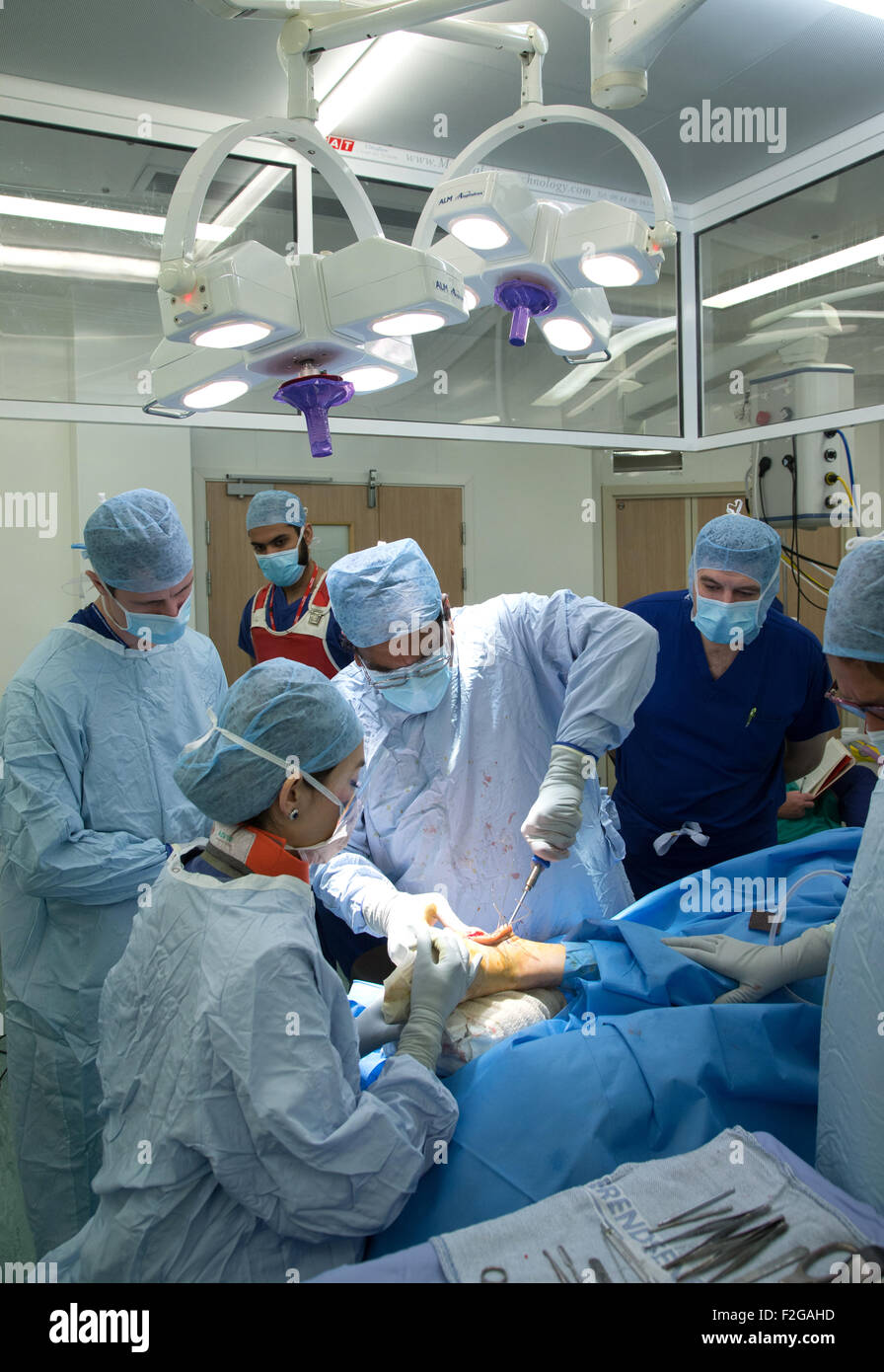 Surgeon and medical staff working in an operating theatre in an NHS hospital Stock Photo