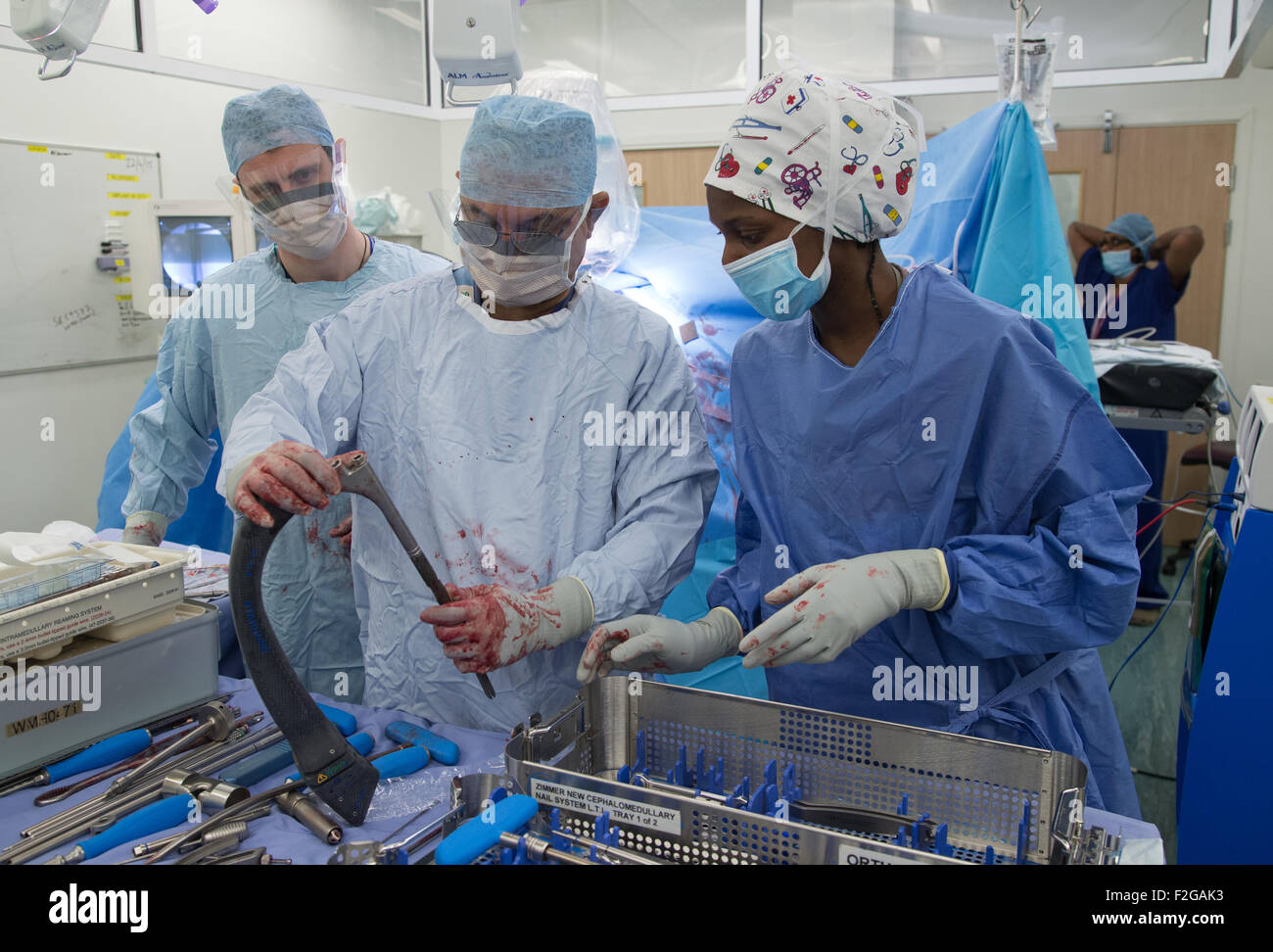 Surgeon and medical staff working in an operating theatre in an NHS hospital Stock Photo