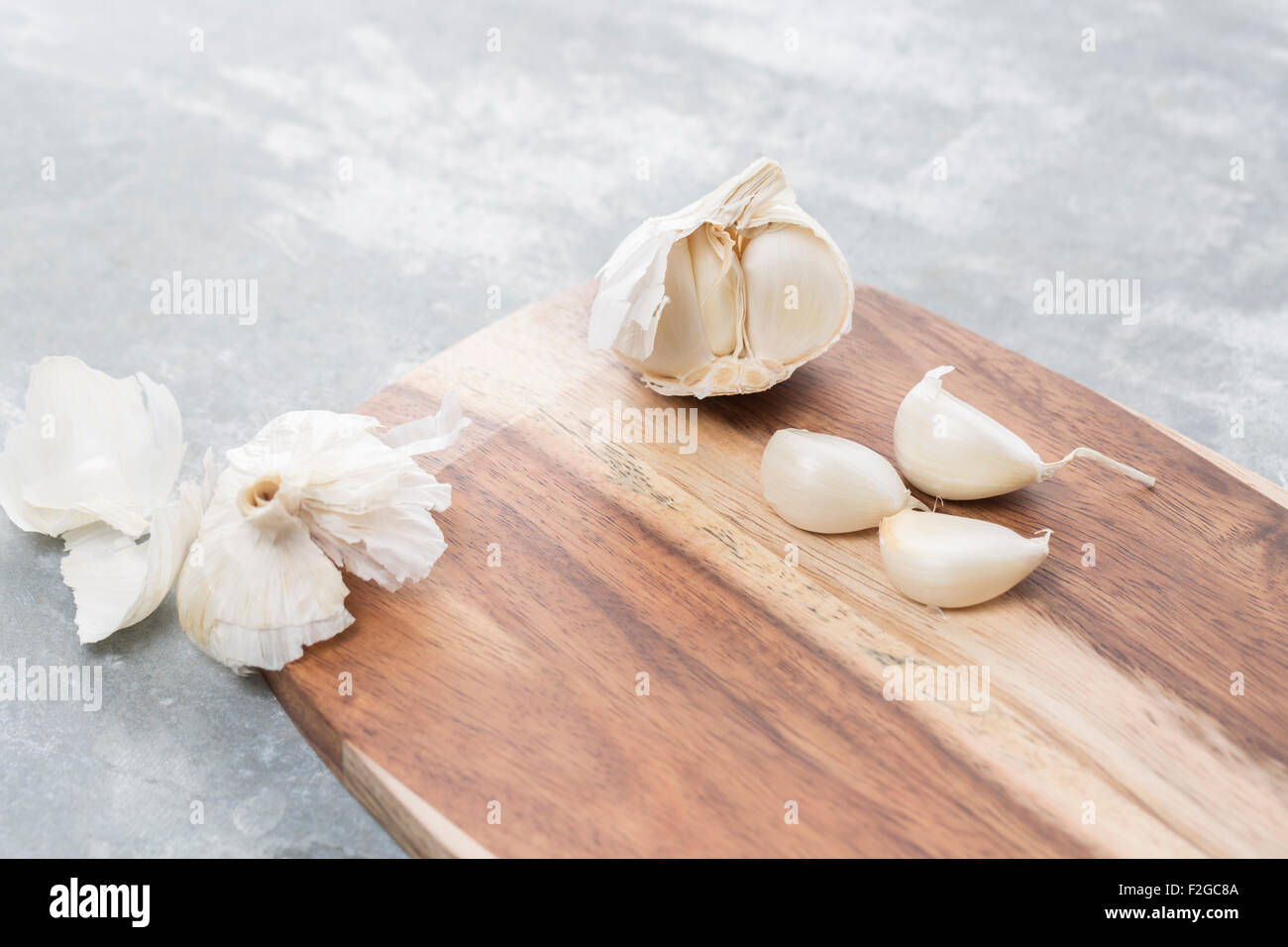 Garlic bulb and single cloves on a wooden board Stock Photo