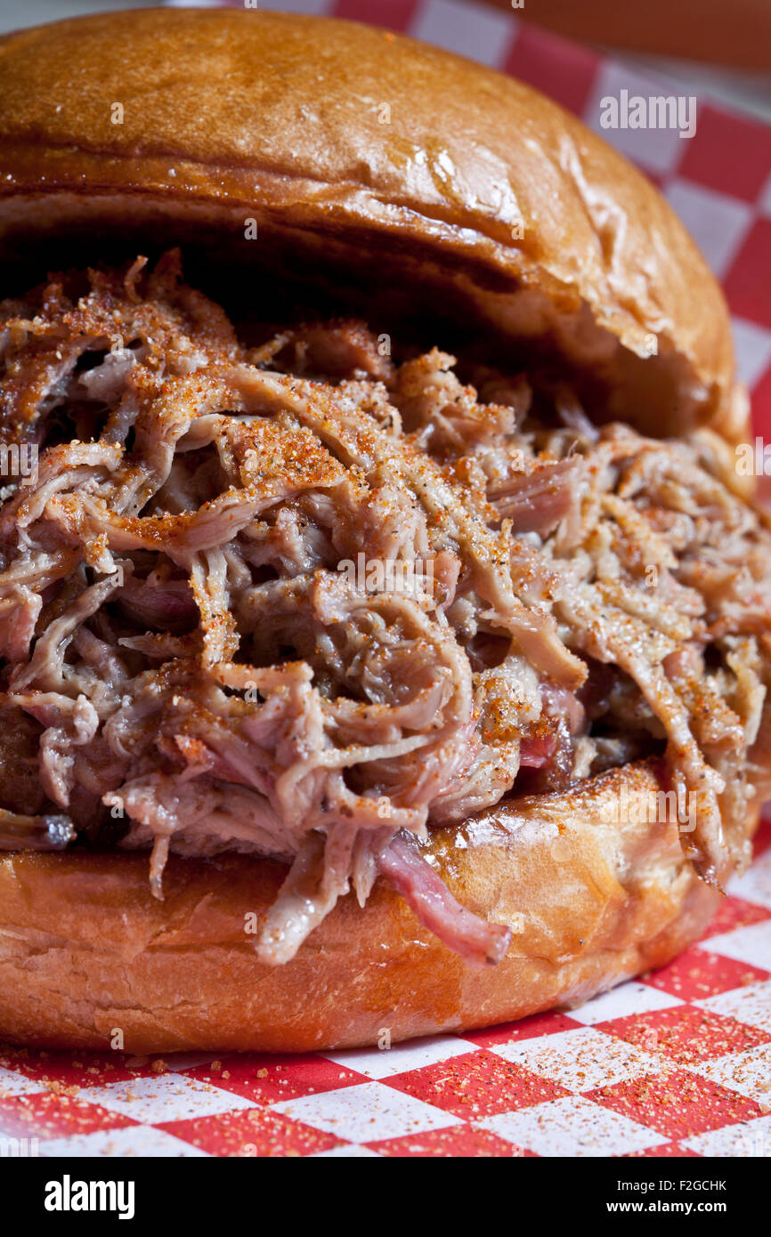 close-up vertical of pulled pork sandwich on red checkered deli paper Stock Photo