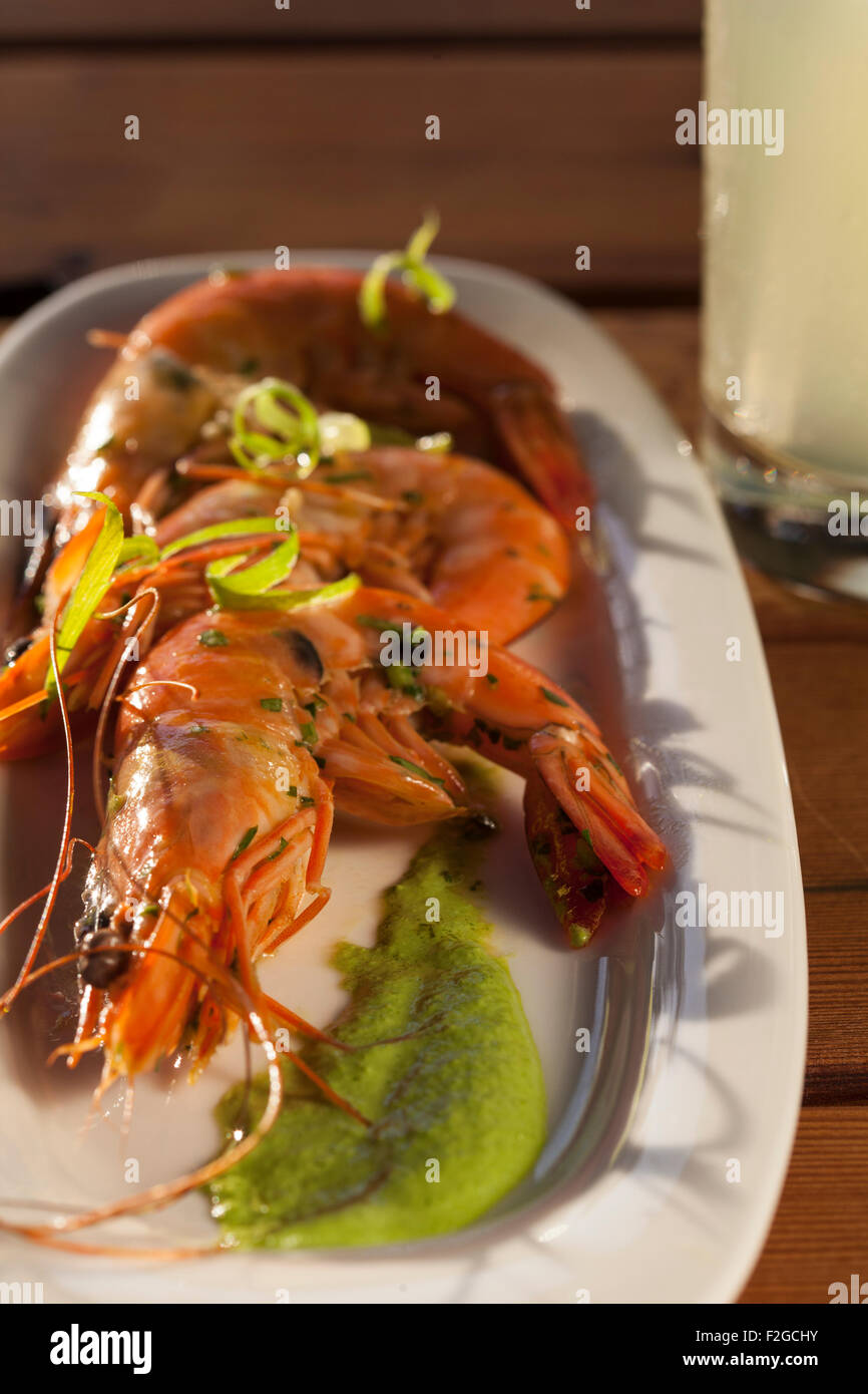 vertical photo of three shrimp on white platter with drink Stock Photo