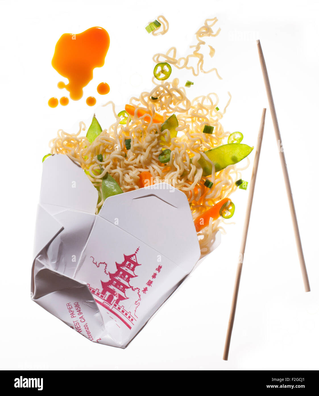 chinese to go noodles coming out of container with soy sauce and chopsticks, back lit on white Stock Photo