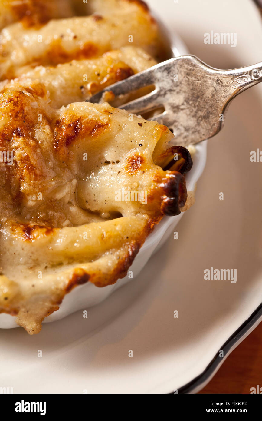 close-up vertical of fork in a baked macaroni and chesse dish with melted cheese and bread crumbs Stock Photo