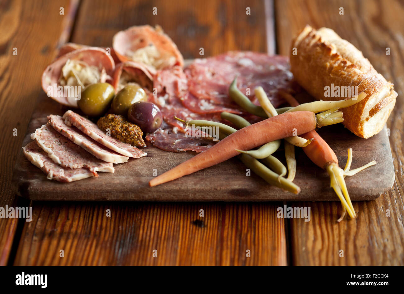 Charcuterie with German Bierwurst with saur kraut, Soppressata salami, pickled vegetables, olives, bread, mustard Stock Photo