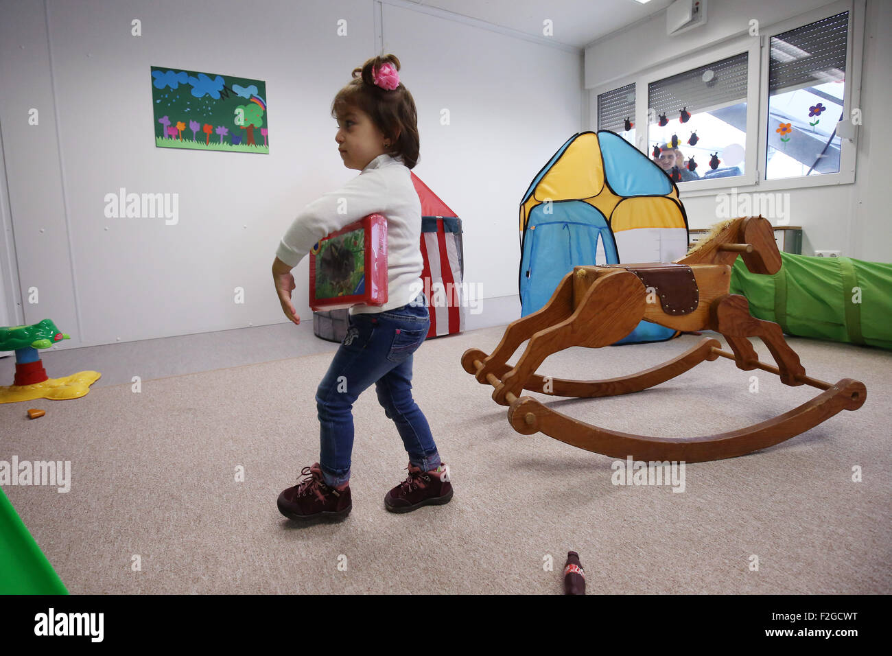 A refugee girl plays with donated toys during a media event in kindergarten of a centralised initial processing station (ZEA) for refugees in Hamburg, Germany 18 September 2015. Children from Bremer Strasse kindergarten have been visited by the German Red Cross (DRK) in the context of 'Aktion Zusammenspiel' (lt: Play Together Campaign) The focus of the Germany-wide campaign is interaction between refugee children and German children. Photo: Christian Charisius/dpa Stock Photo