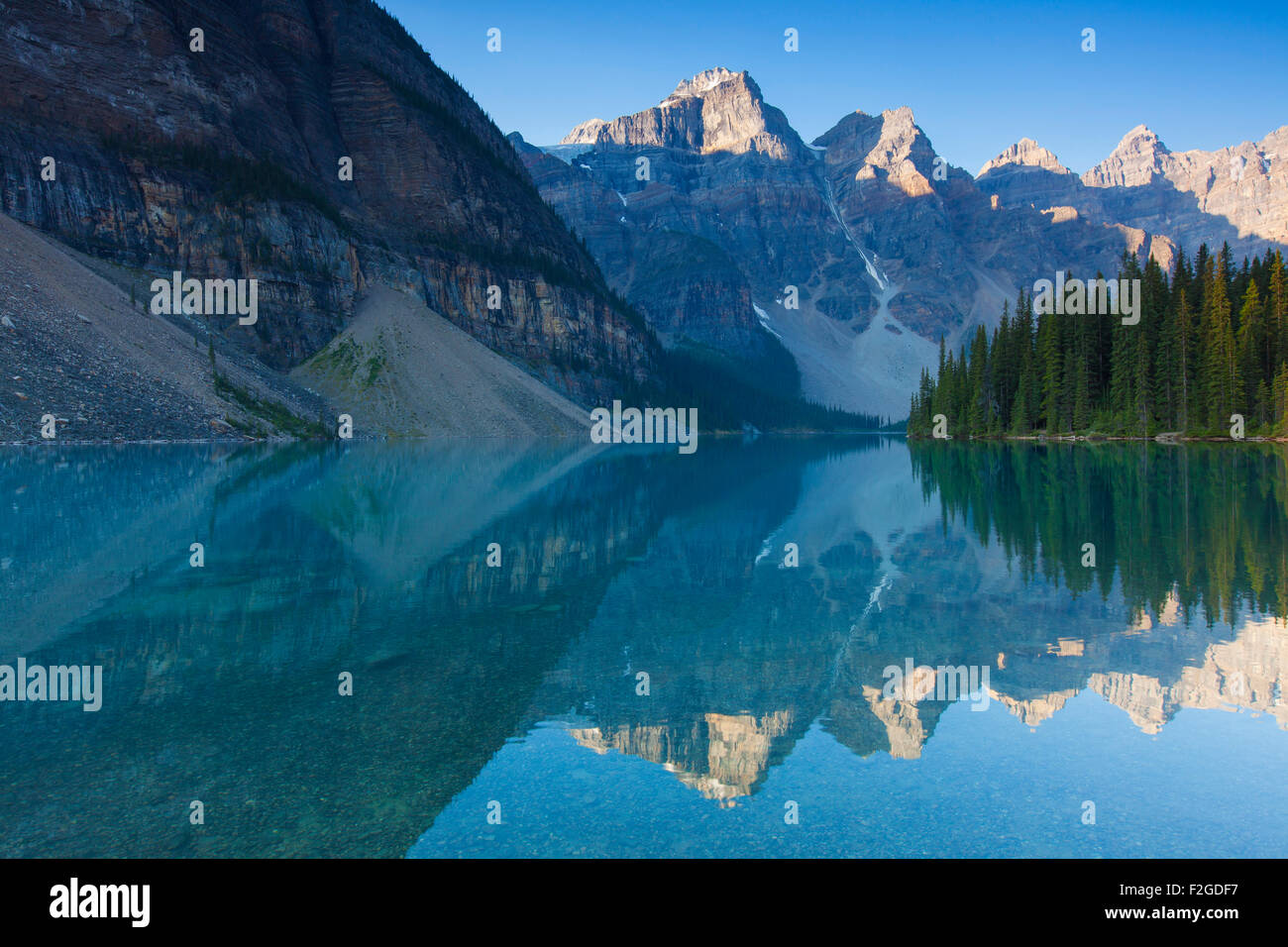 Mountains reflected in glacial water of Moraine Lake in the Valley of the Ten Peaks, Banff National Park, Alberta, Canada Stock Photo