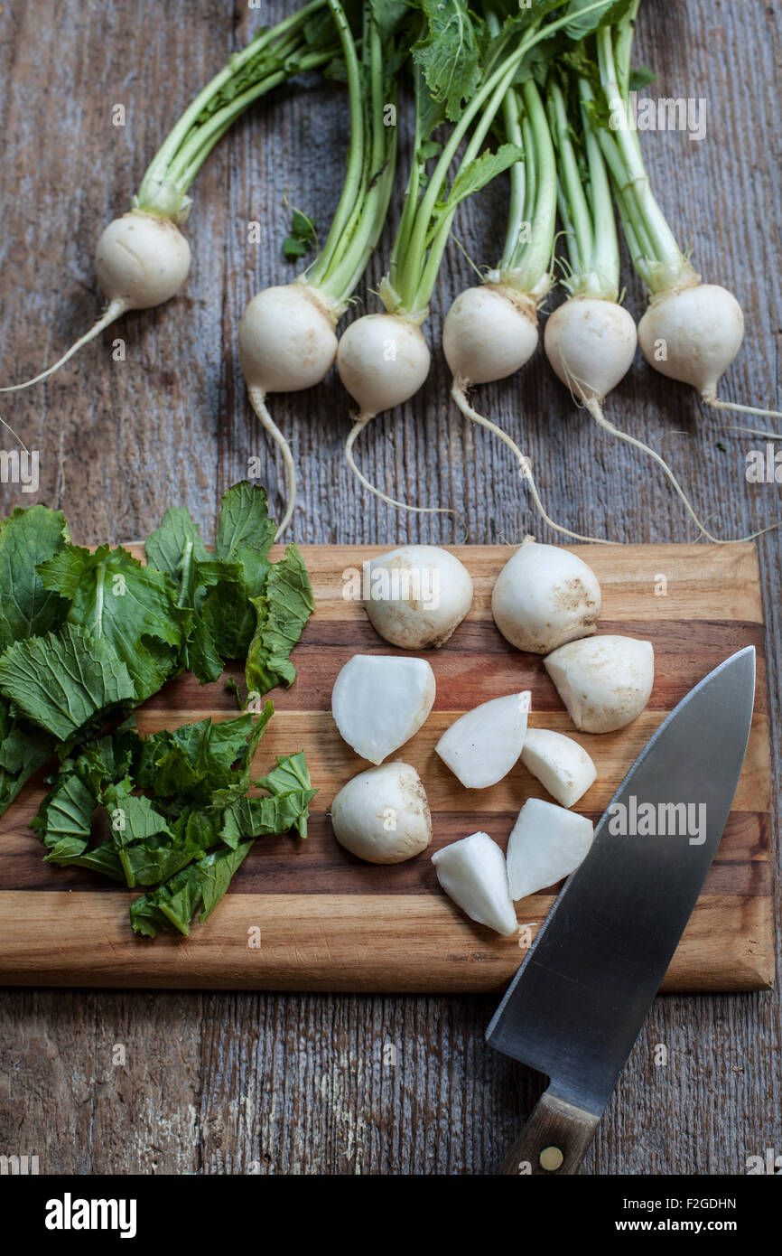 Tokyo Turnips chopped and whole with greens on cutting board Stock Photo