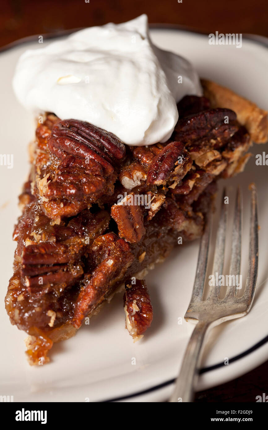 slice of pecan pie with whipped cream on plate with fork Stock Photo