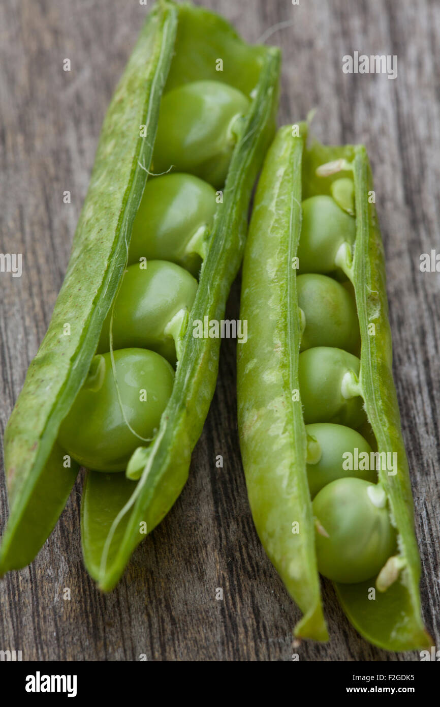 close-up two fresh peas in pods on rough wood Stock Photo