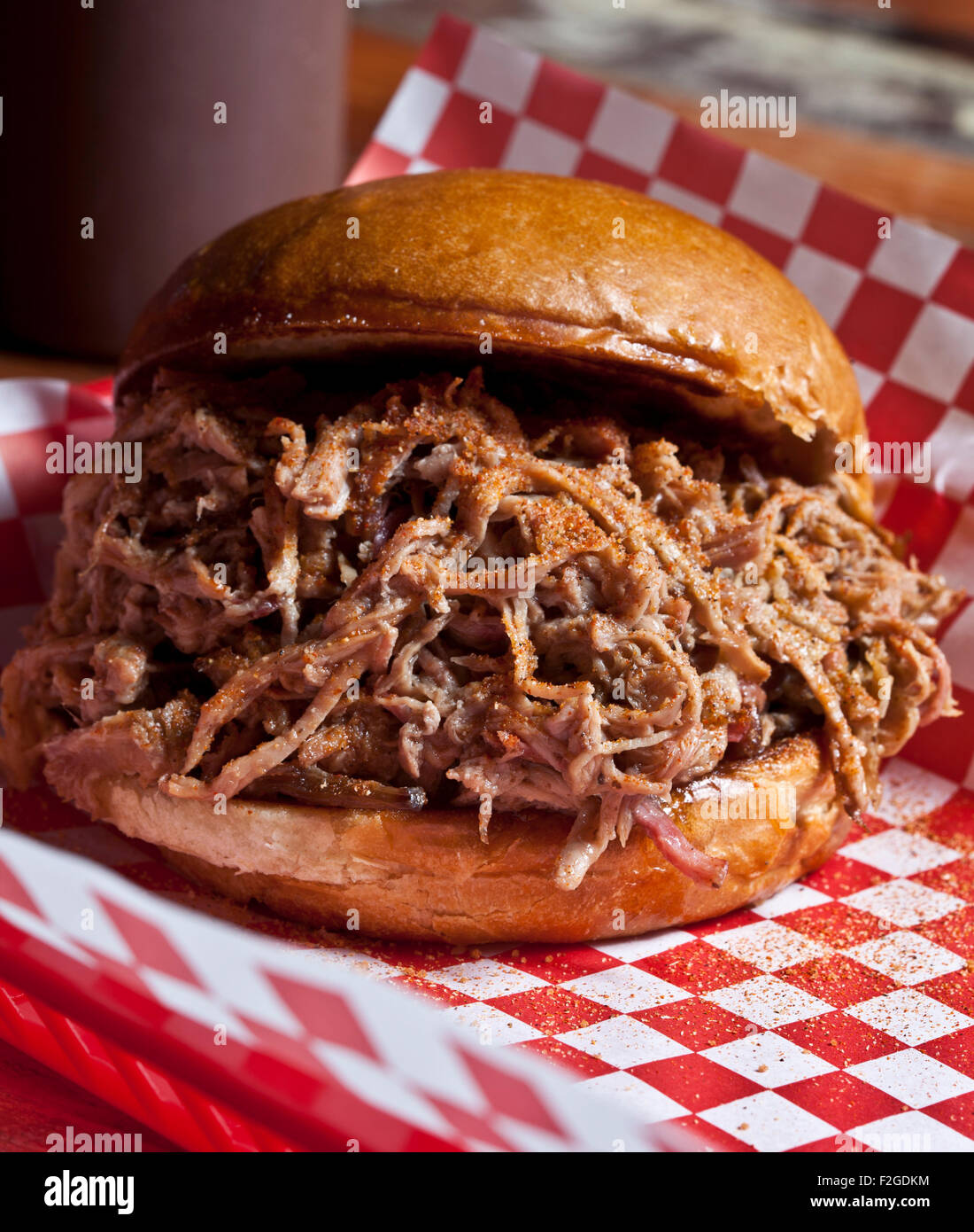 pulled-pork sandwich on a bun on red and white checked paper Stock Photo