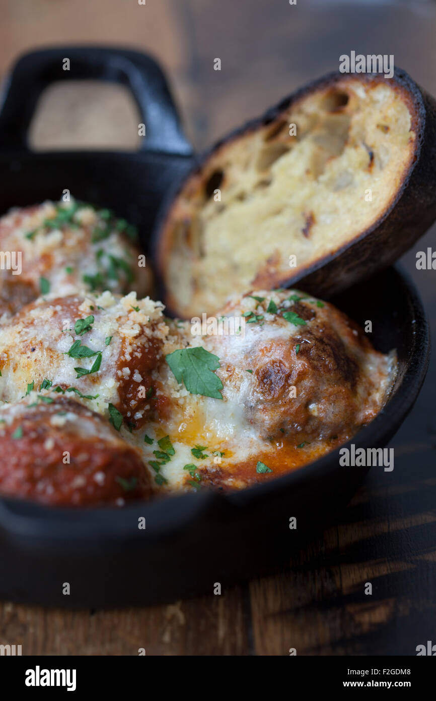 meatballs with cheese sauce in iron skillet with bread Stock Photo