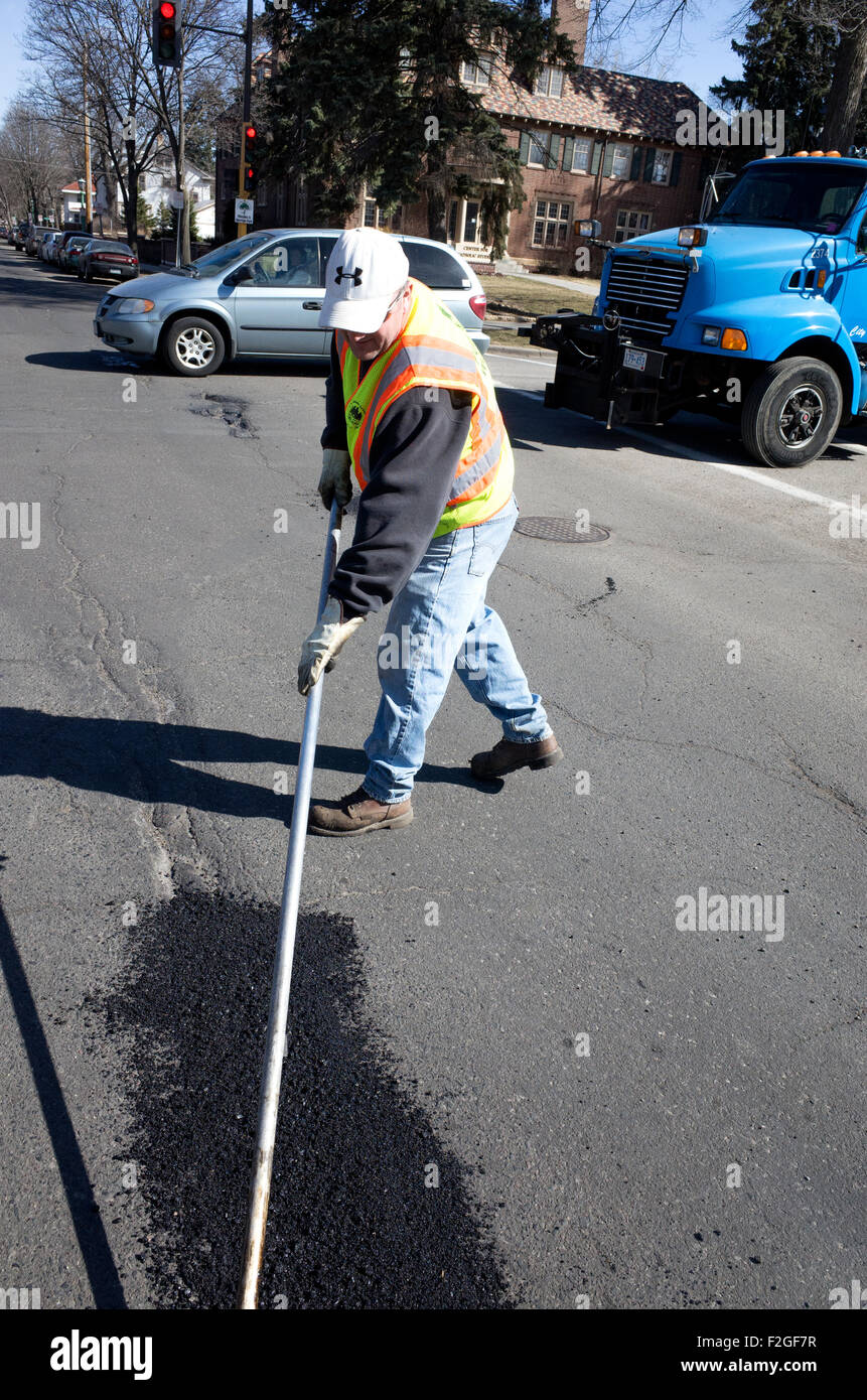 Working man smoothing out asphalt patch on pothole in city street. St Paul Minnesota MN USA Stock Photo