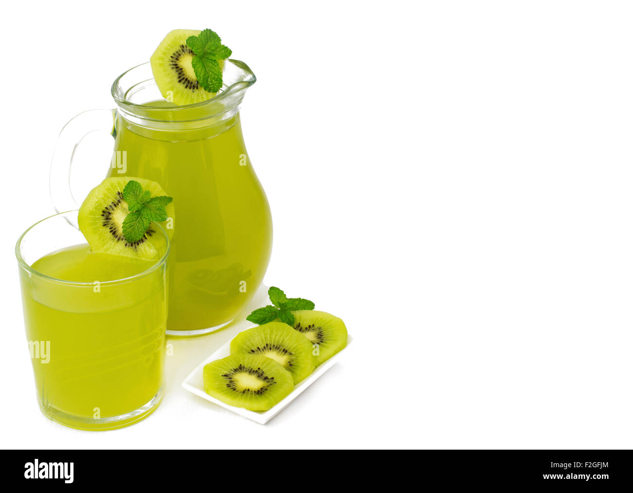 A healthy lifestyle refreshing Kiwi drink, the juice is shown in a glass and a jug on an isolated white background with slices Stock Photo