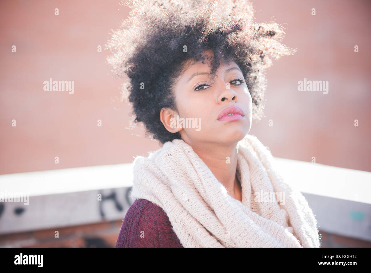 Portrait of a young beautiful black curly hair african woman in town ...