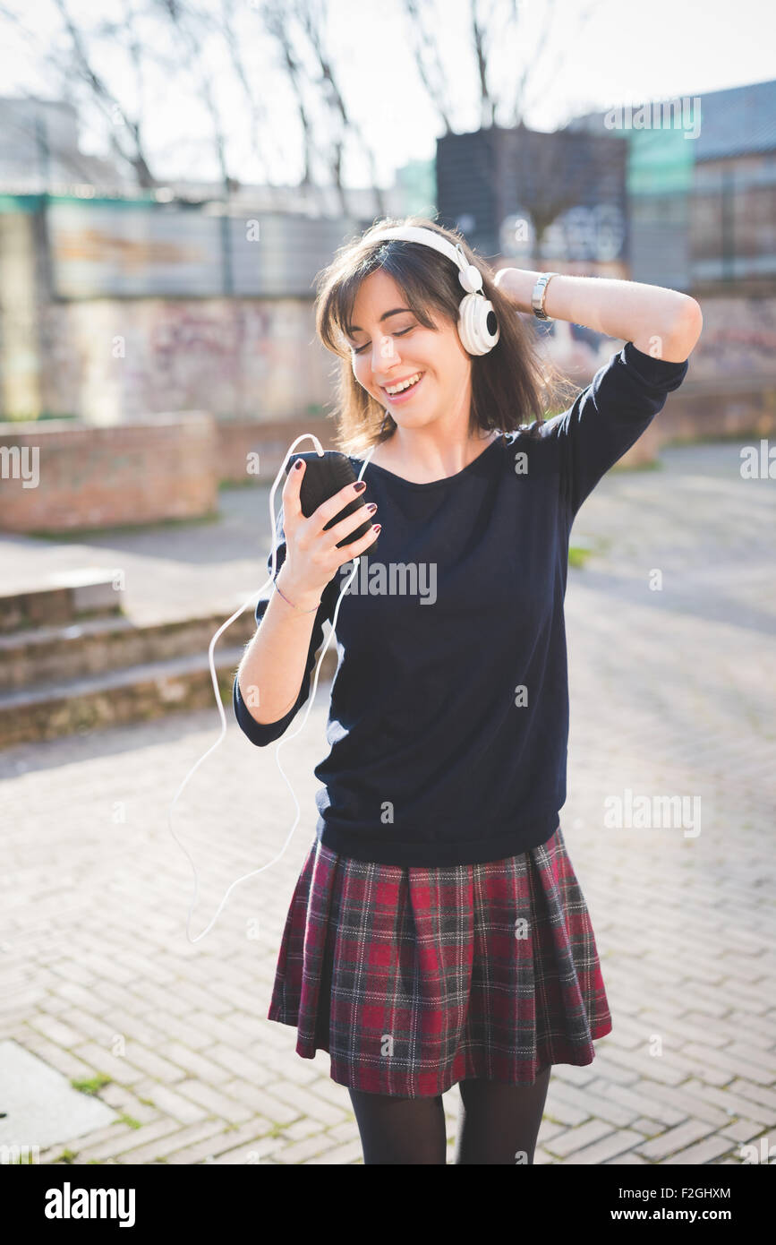 Knee figure of a young pretty brown hair caucasian girl listening music