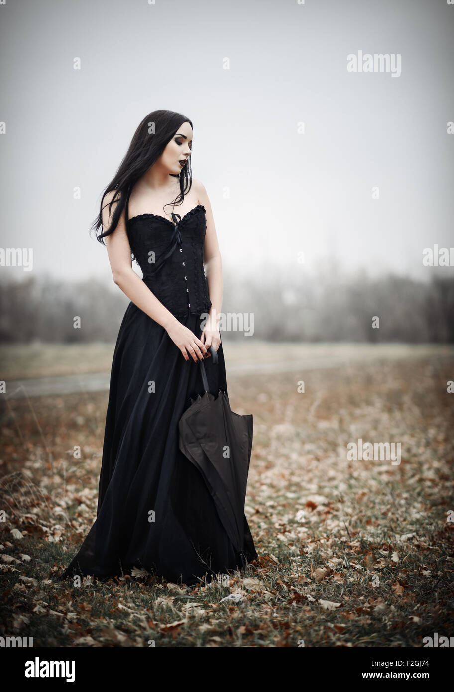 A beautiful sad goth girl holds black umbrella Stock Photo