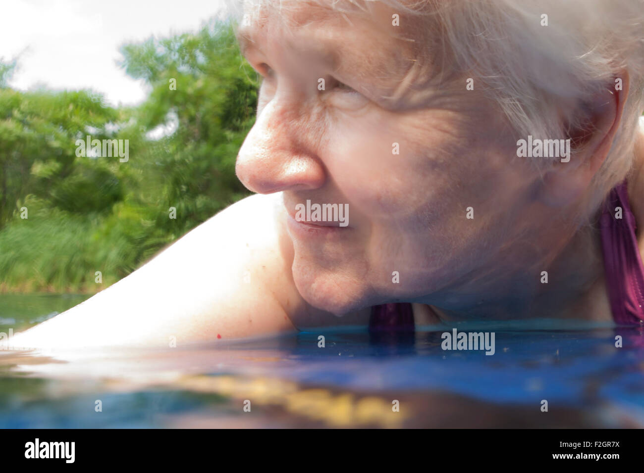 An elderly woman swims in a pond. Stock Photo