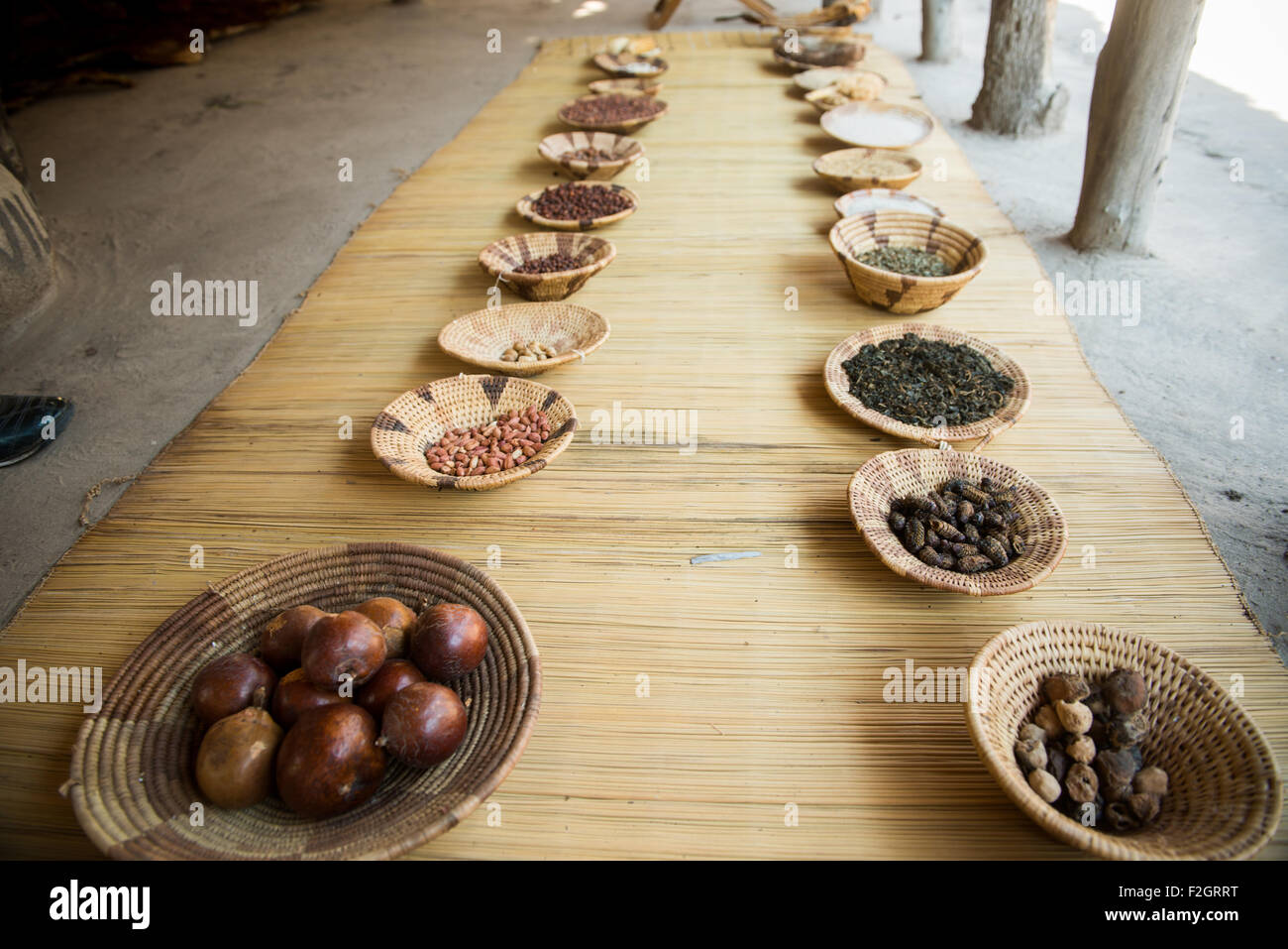 Two rows of dried food in handwoven bowls on a wicker mat in Botswana, Africa Stock Photo