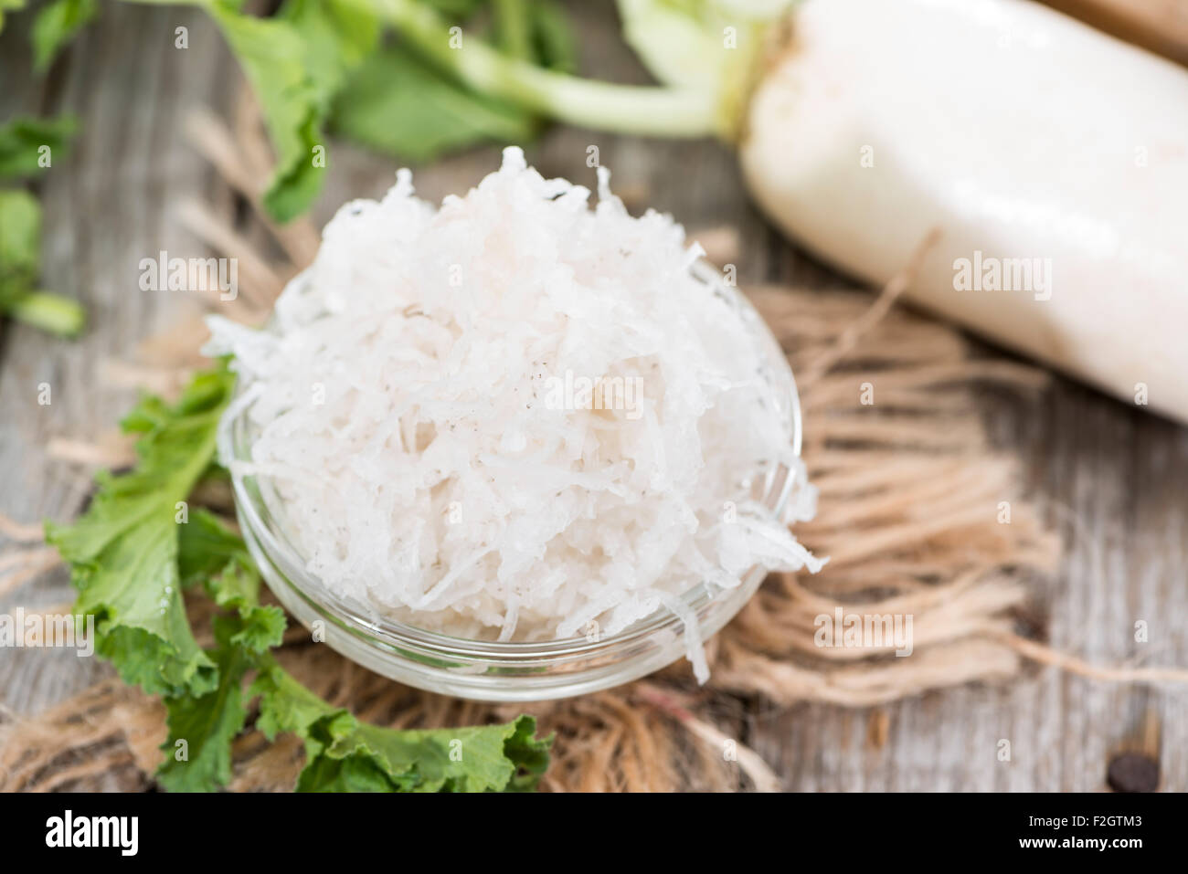 Fresh grated Horseradish on wooden background (detailed close-up shot) Stock Photo